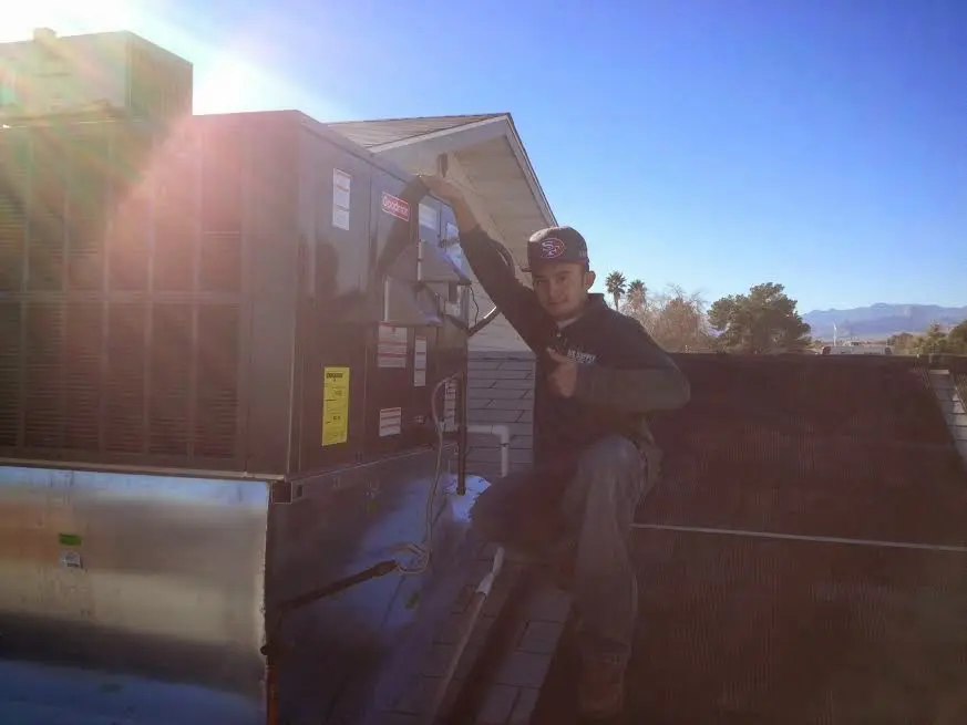 HVAC technician performing AC Tune-Up on a rooftop unit in Pella