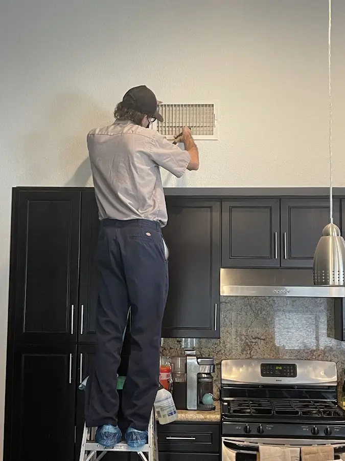 Technician inspecting an air vent during HVAC service in Pella